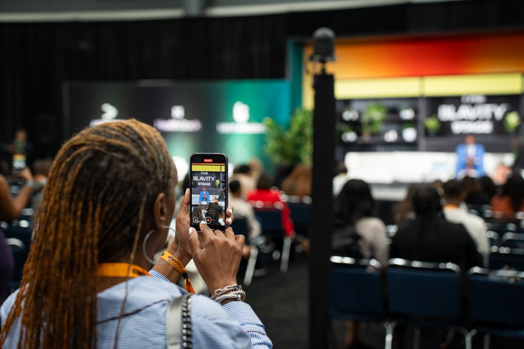 Attendee photographing a speaker on the Blavity Stage at AfroTech